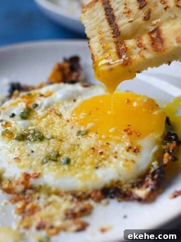 Fried egg with bread being dunked in a runny yolk.