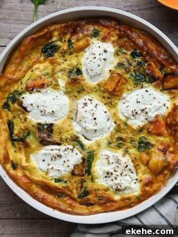 Overhead of a cooked frittata in a white skillet on a wood surface.