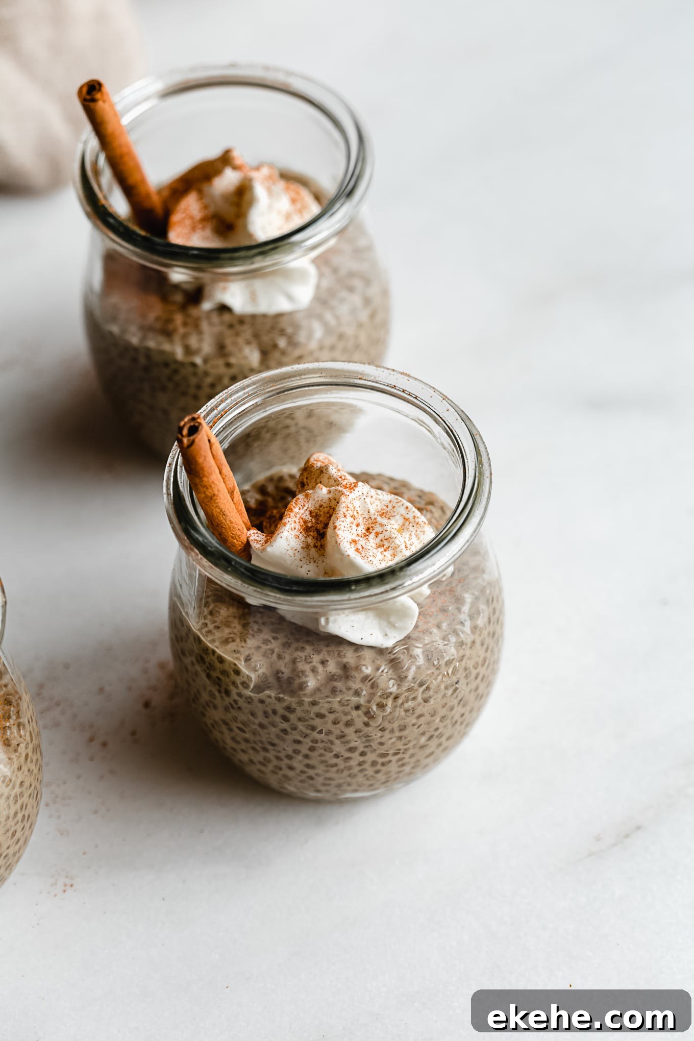 two jars of gingerbread chia pudding topped with whipped cream and cinnamon