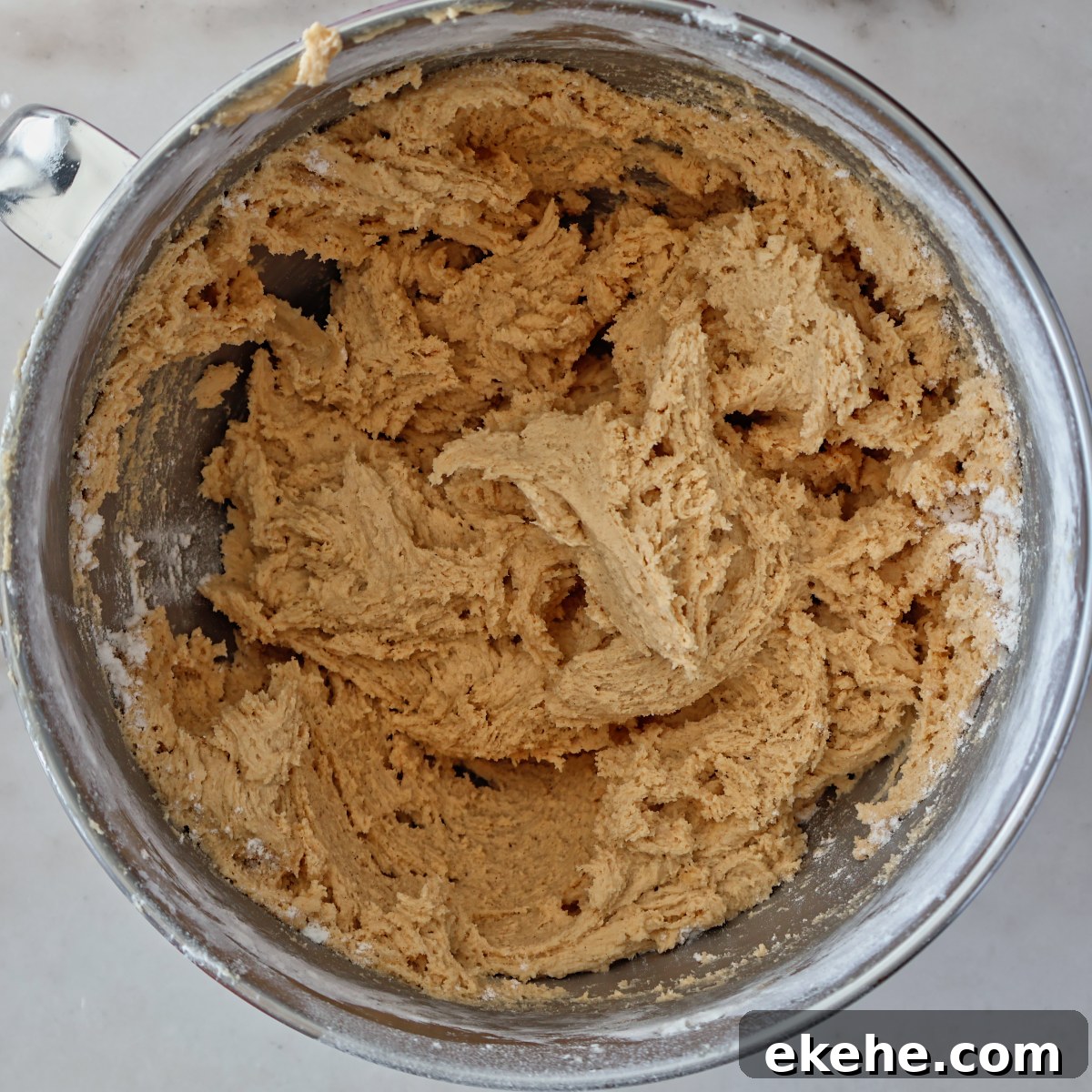thick light brown cookie dough in stainless steel stand mixer bowl.