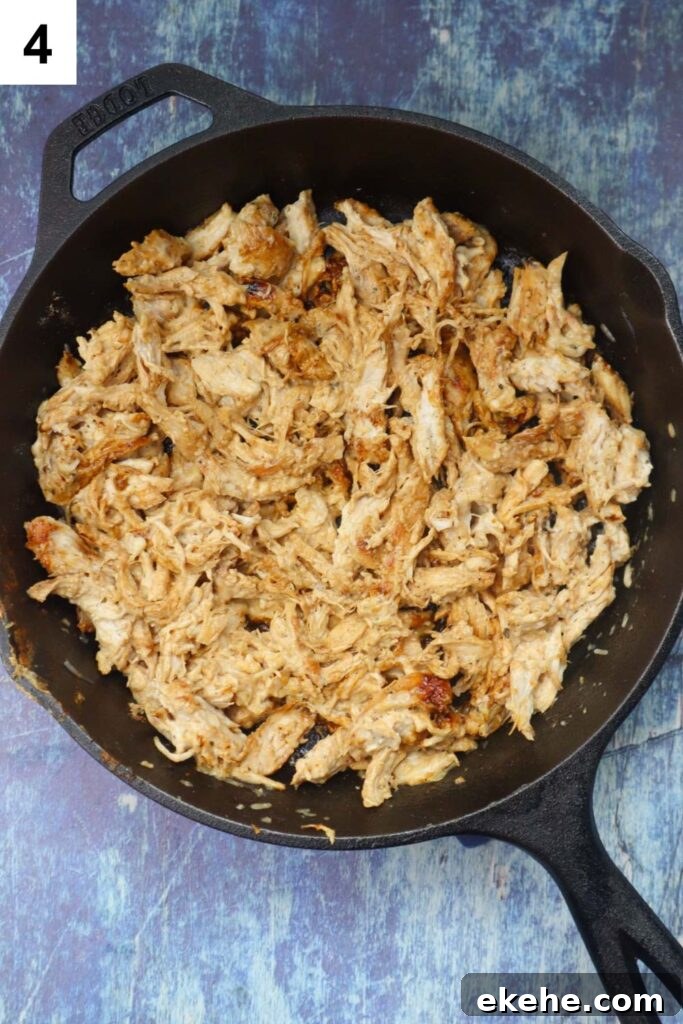 cast iron skillet with shredded chicken, gouda cheese, and ranch dressing