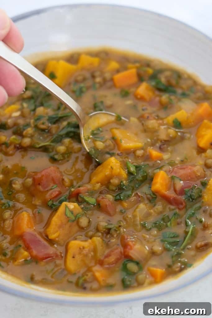 a close up of Hearty Lentil Soup with Roasted Butternut Squash, Kale and Bacon in a bowl with a spoon