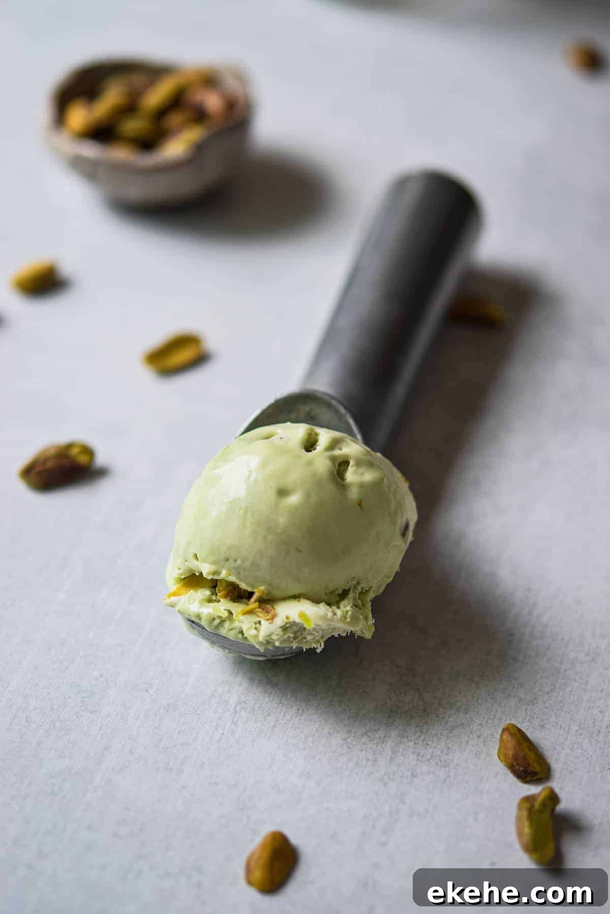 Scoop of pistachio ice cream on a metal ice cream scoop.