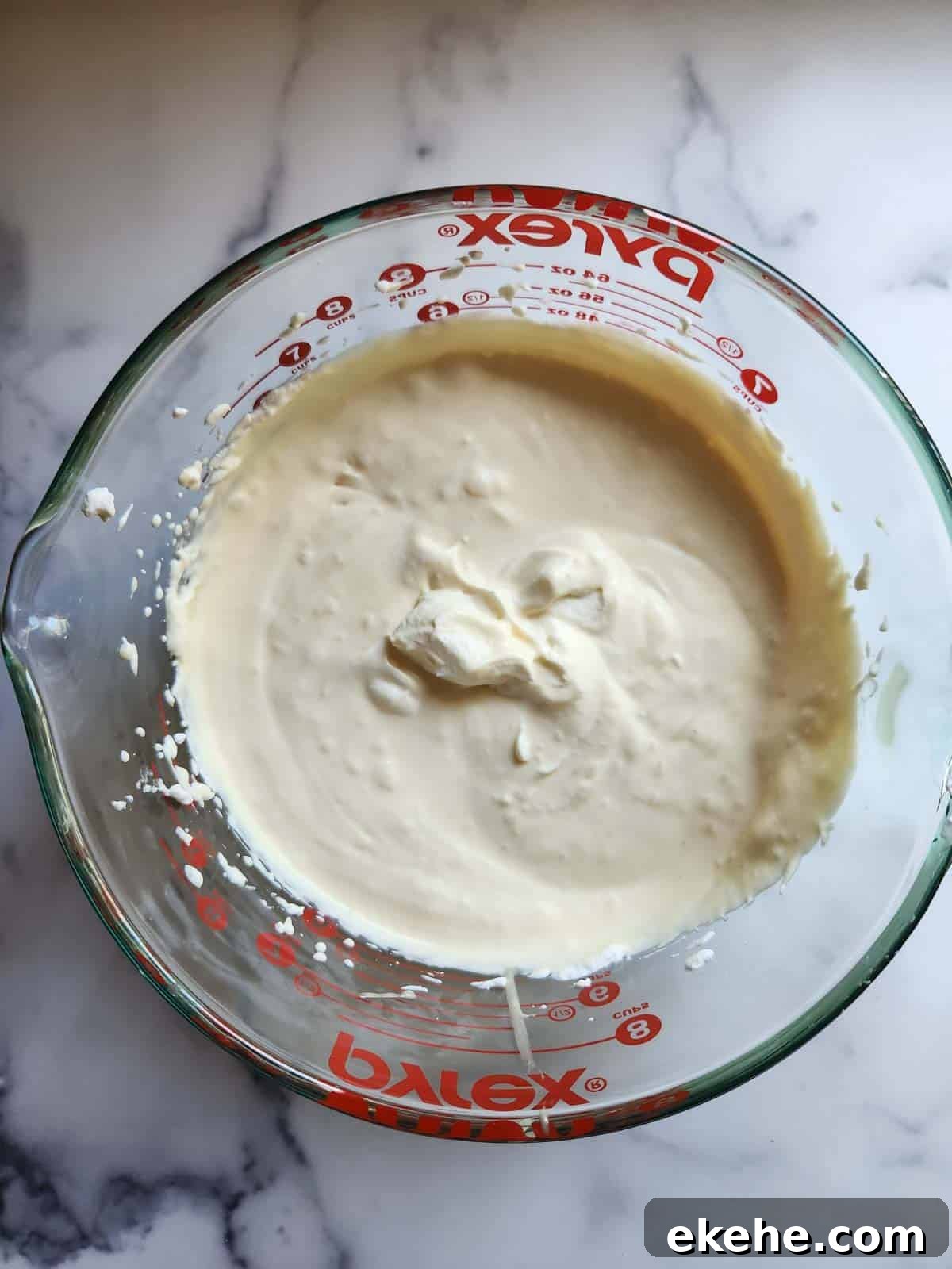 Whipped cream and condensed milk in a clear bowl.