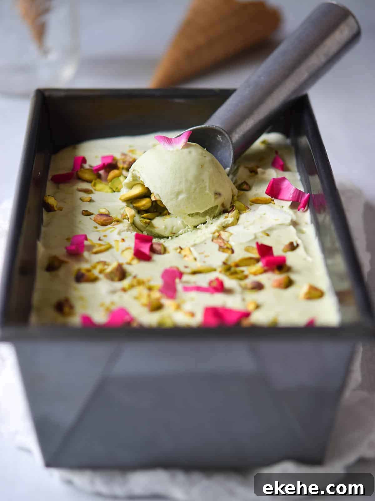 Pistachio ice cream in a loaf pan with rose petals on top.