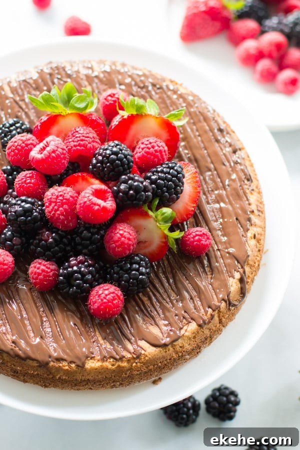 An overhead image of an almond cake with berries on a cake stand.
