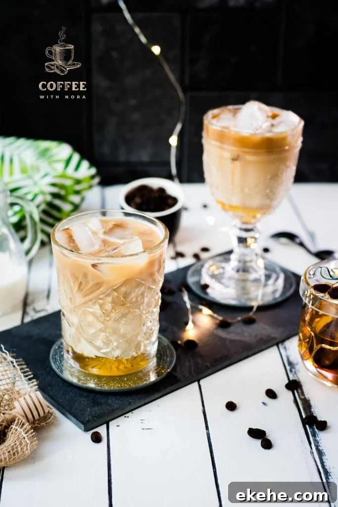 Gorgeous glasses filled with iced honey latte placed on dark slate plate.