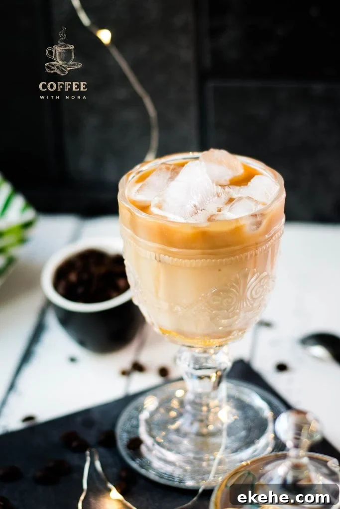 Gorgeous glass filled with iced honey latte placed on dark slate plate.