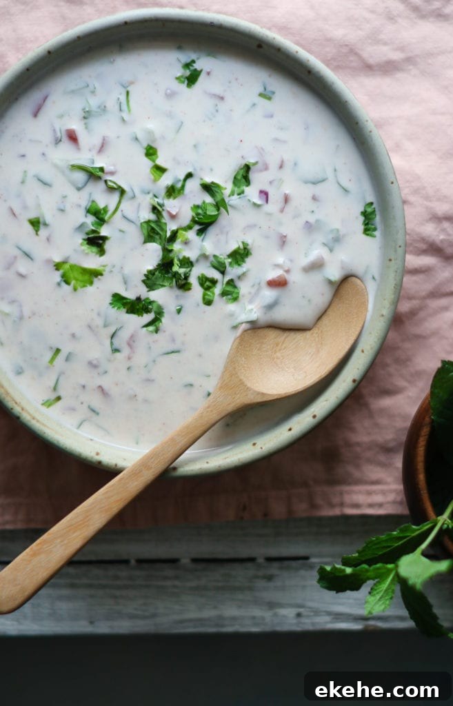 Cucumber Raita in a bowl with a wooden spoon and cilantro sprinkled on top