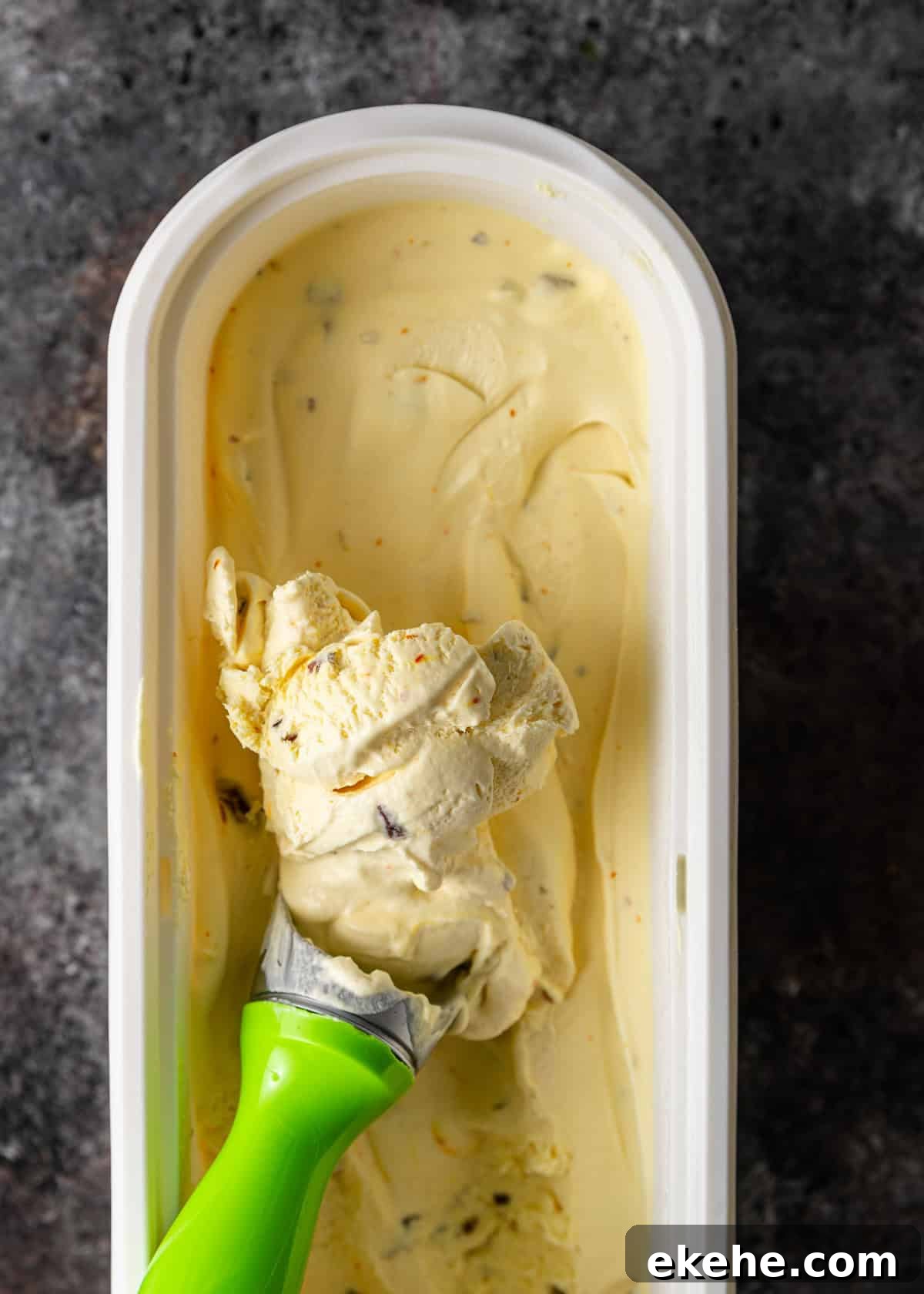 overhead: scooping out pistachio ice cream from the tub