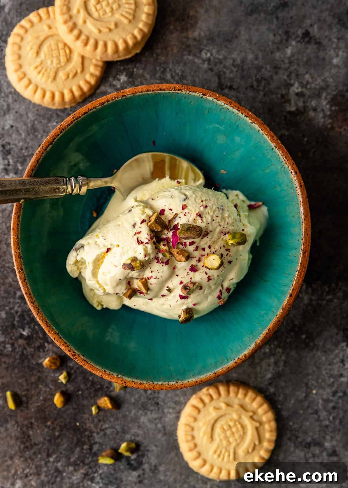 overhead: a few scoops of persian ice cream topped with crushed pistachios and rose petals in a blue bowl with a spoon