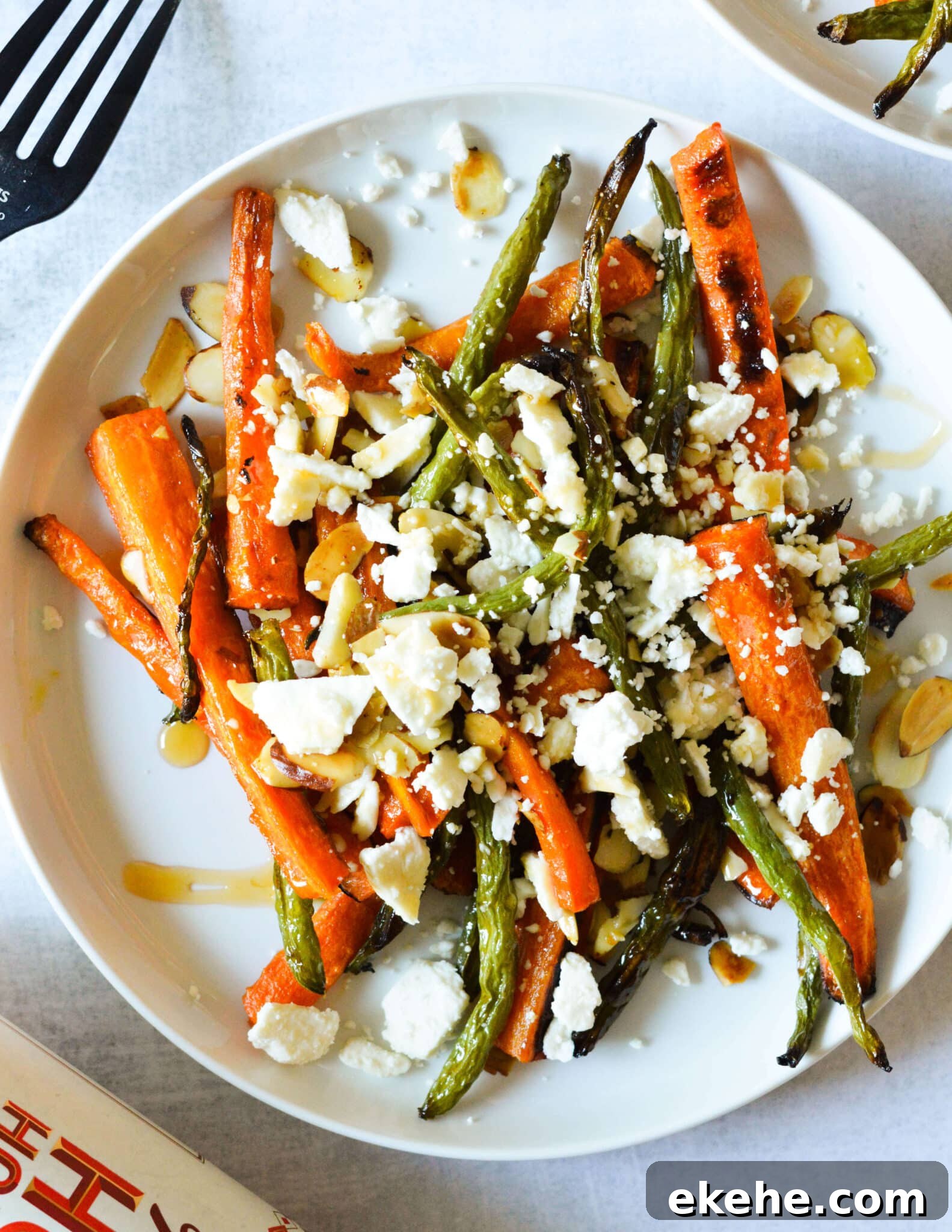 a plate with roasted carrots and green beans, feta, toasted almonds, and hot honey.