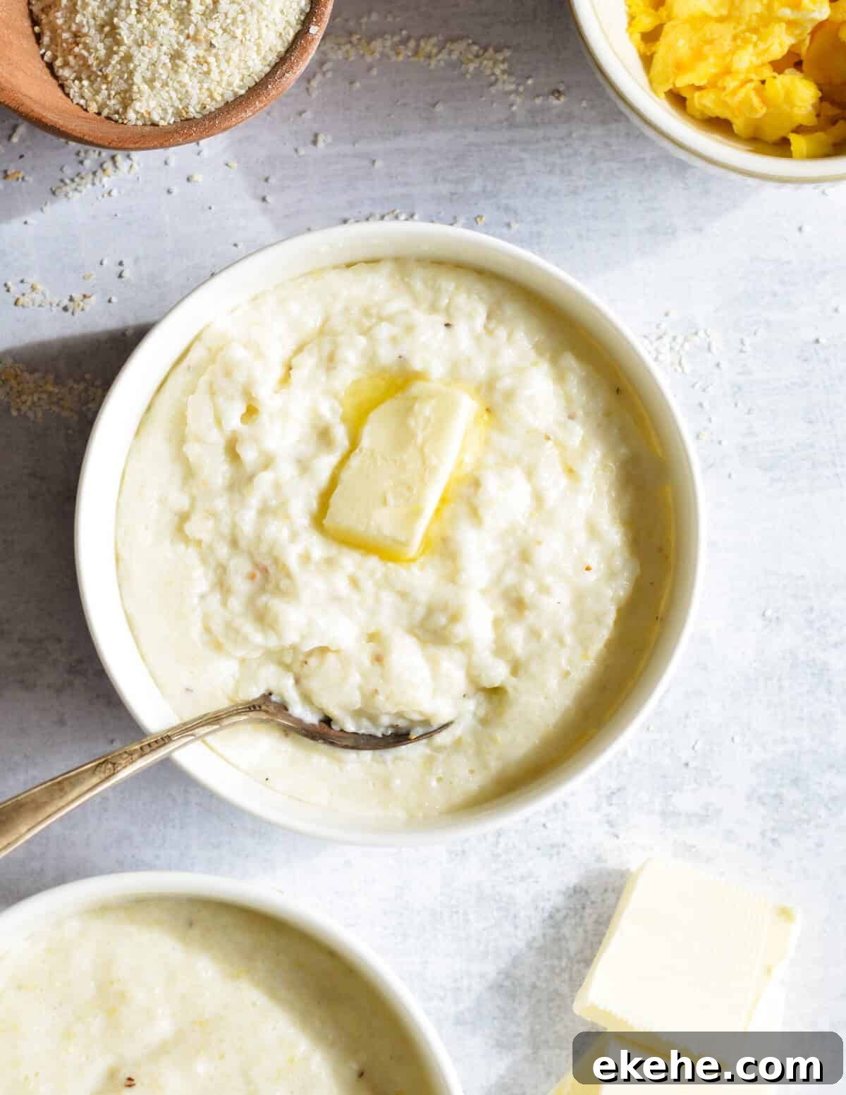 a bowl of grits with a slice of butter on top. 