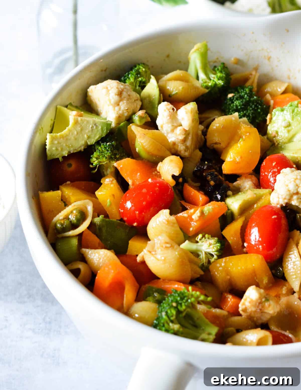 a bowl of pasta salad with veggies and tomatoes.