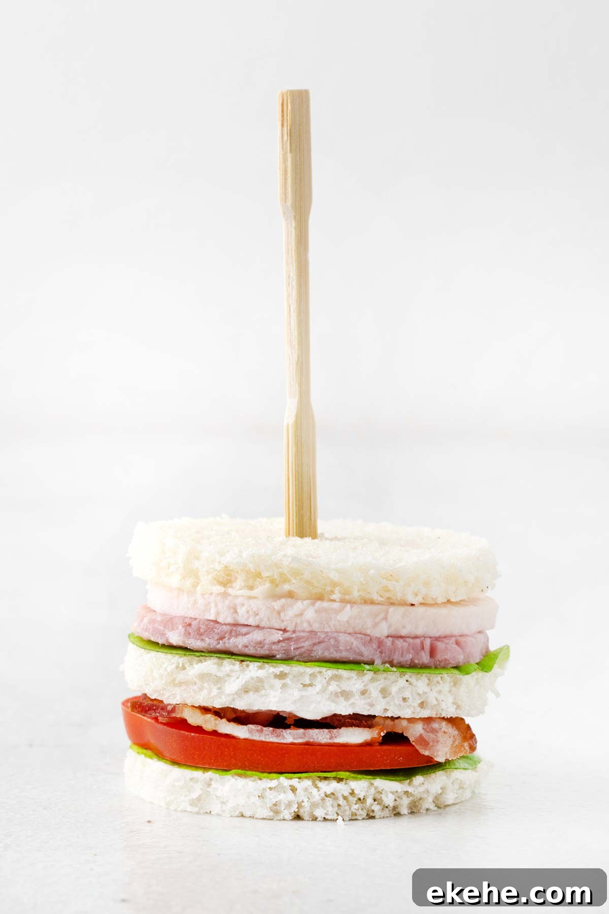 Completed club tea sandwich skewered with a cocktail fork. 