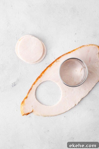 Sliced turkey being cut into circles with a round cookie cutter.