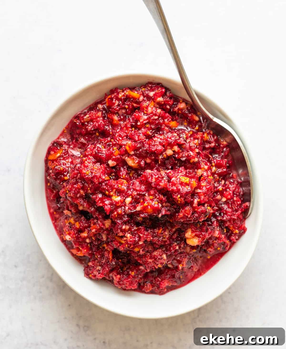 Cranberry Orange Relish served in a white bowl with a silver spoon.