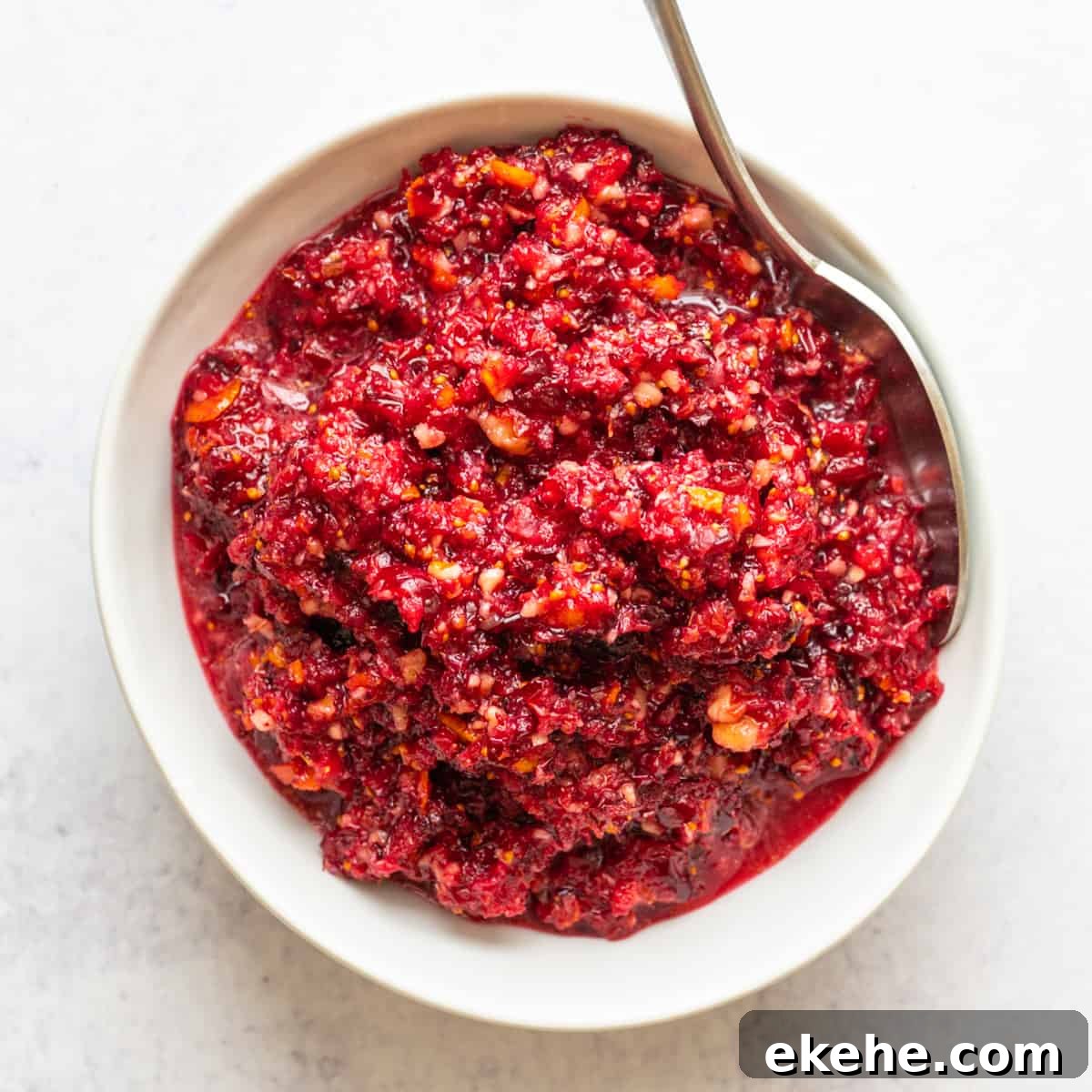 Cranberry Orange Relish served in a white bowl with a silver spoon.