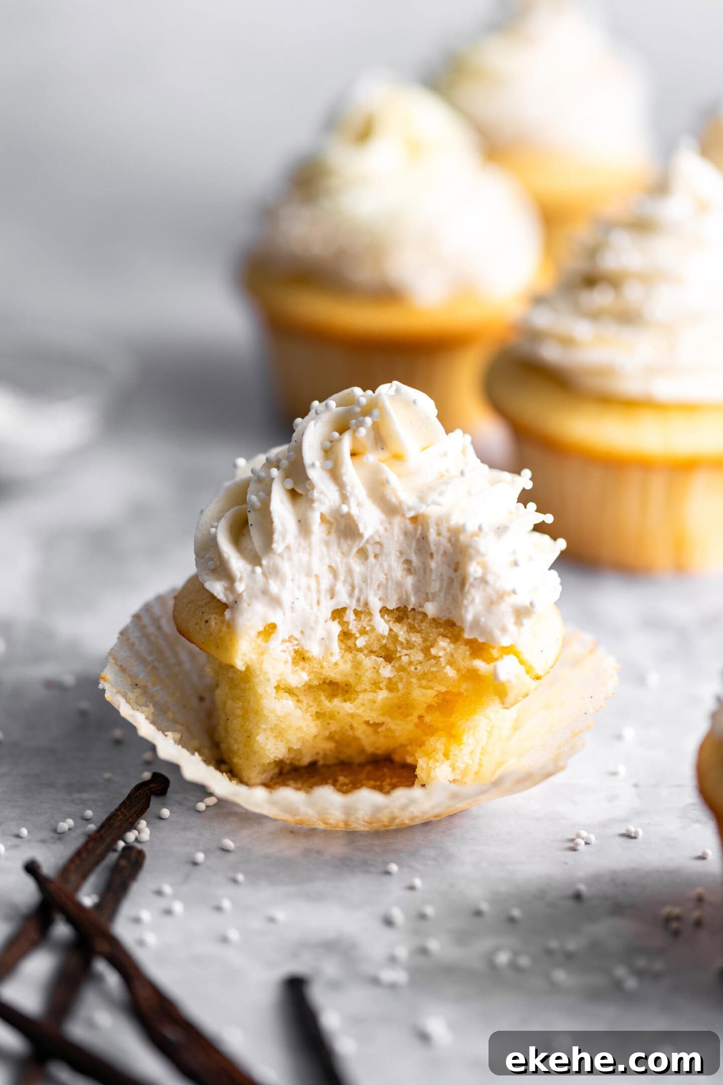 Close up of vanilla cupcake with double vanilla buttercream on top with a bite missing