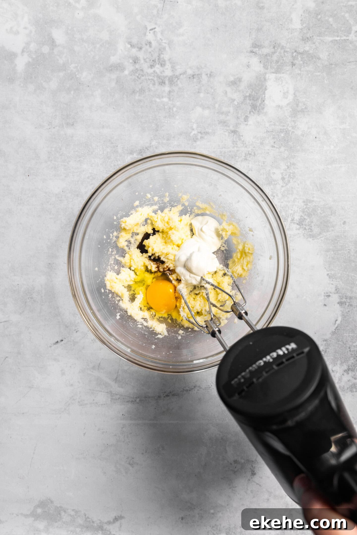 Egg, sour cream, and vanilla bean paste being beaten into the butter and sugar mixture