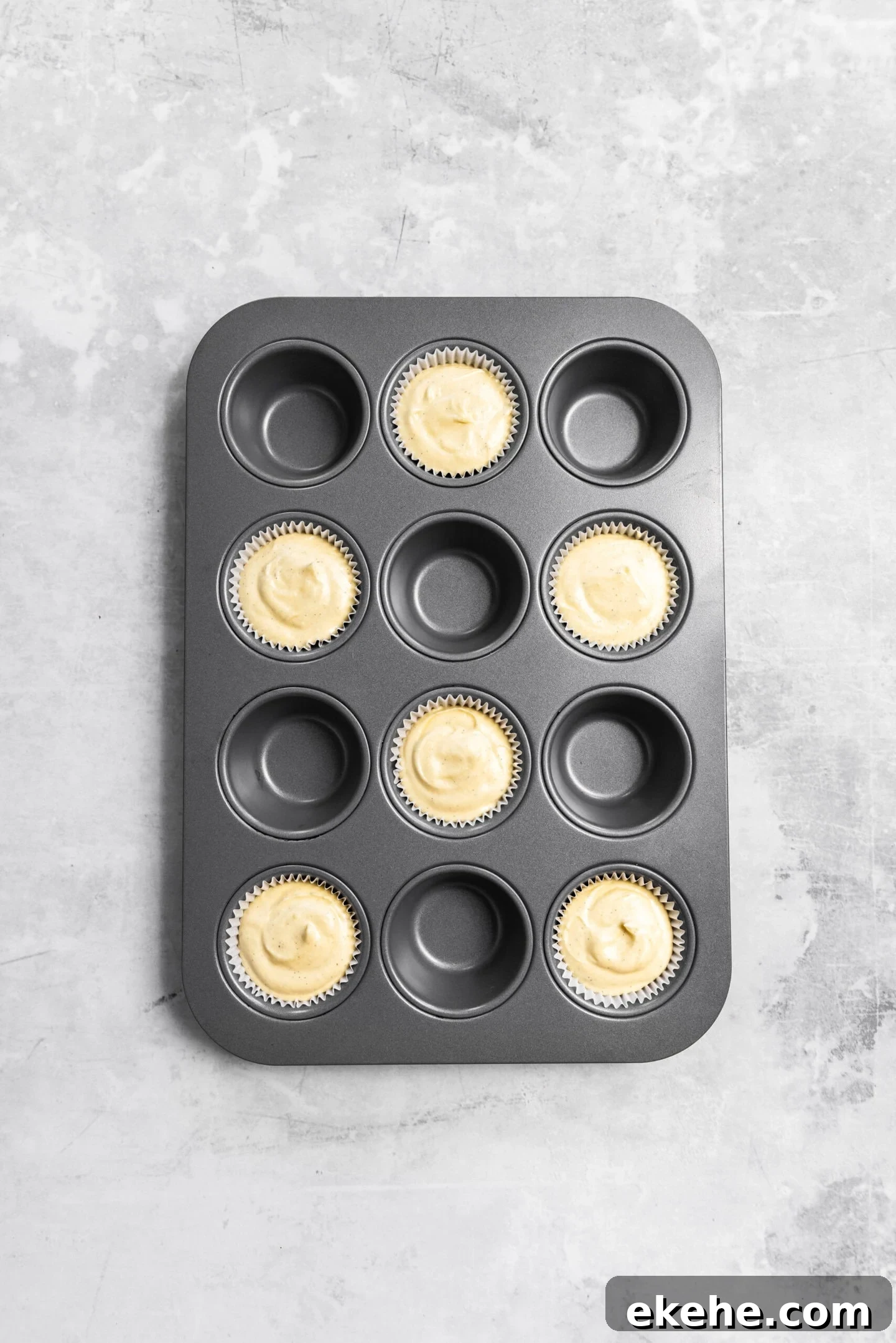 Cupcake batter in prepared muffin tin with smooth tops ready for the oven.