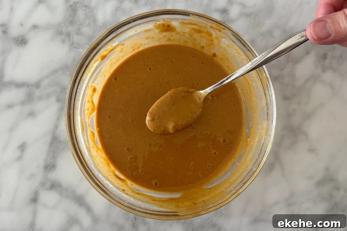 Mixed spicy peanut sauce with PB2 for peanut noodles in a bowl.