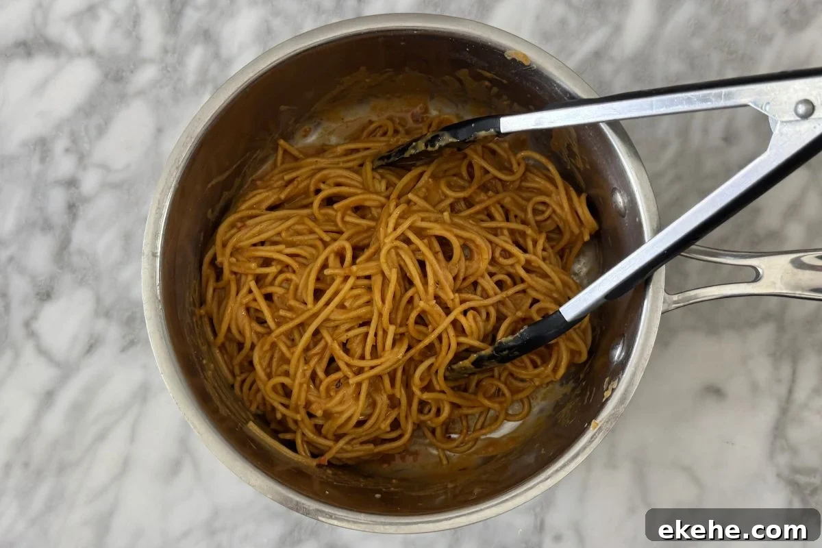 Coated spicy peanut noodles in a saucepan.