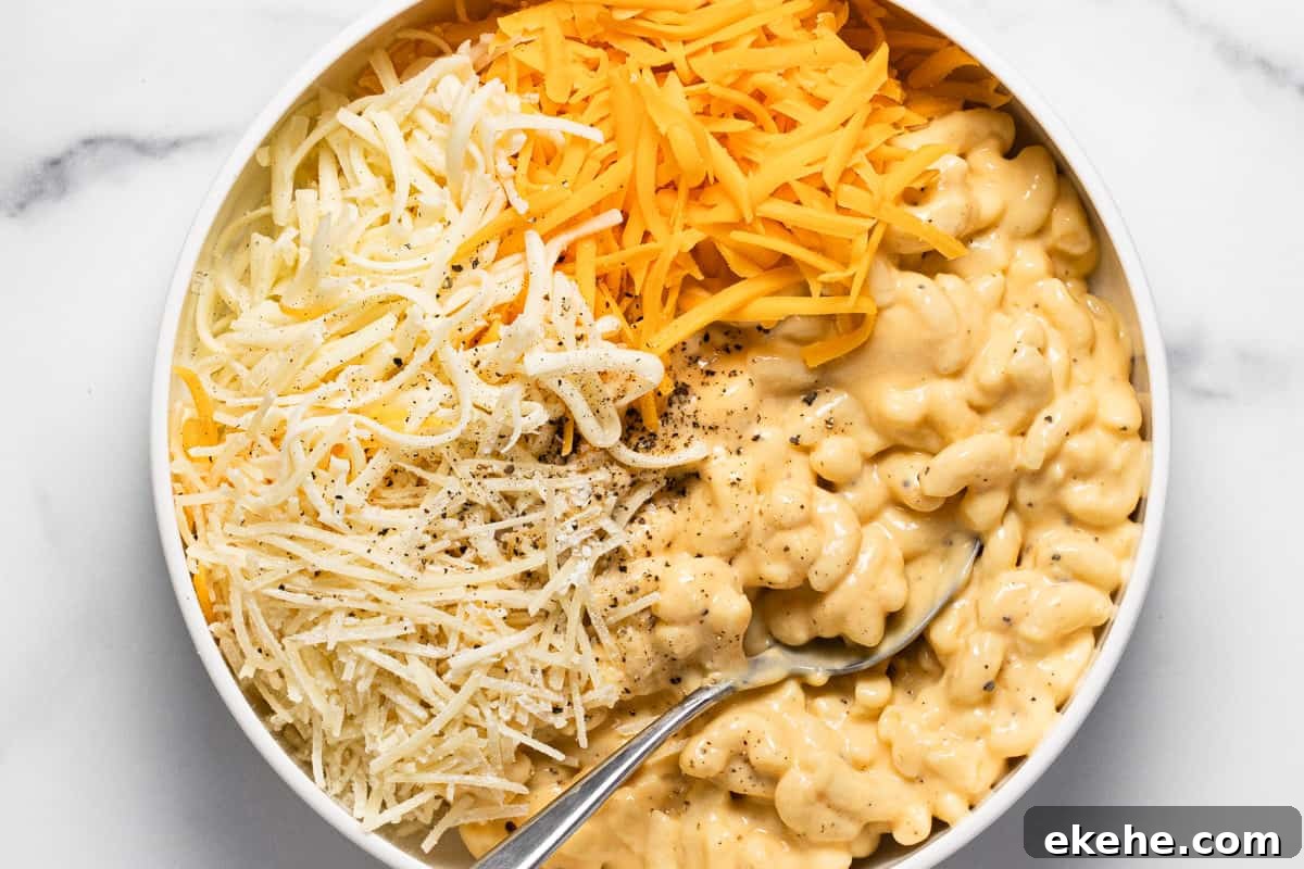 White bowl filled with mac and cheese and shredded cheese