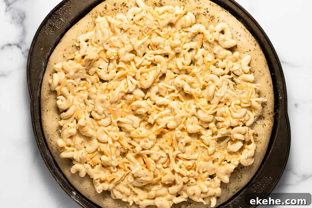 Pizza crust on a pizza pan topped with macaroni and cheese