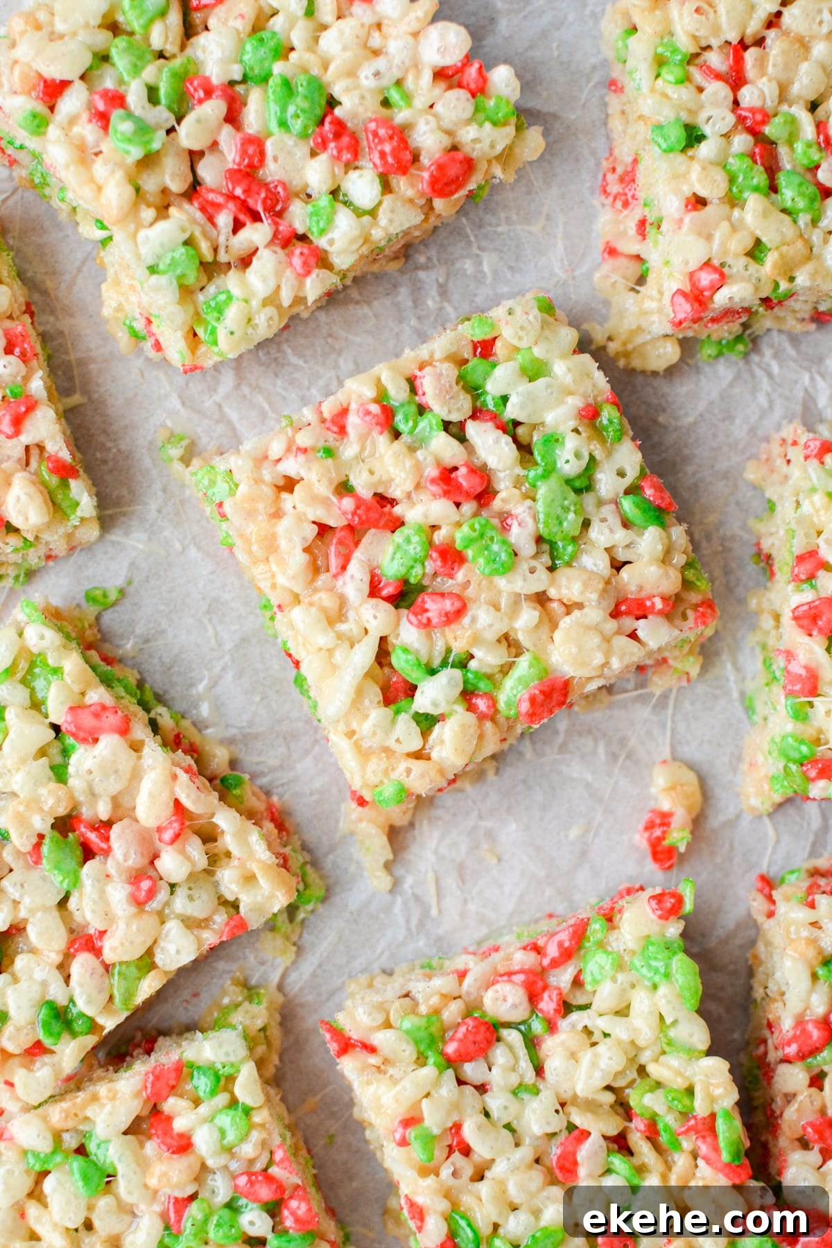 An overhead view of holiday Rice Krispie treats on a parchment lined baking sheet.