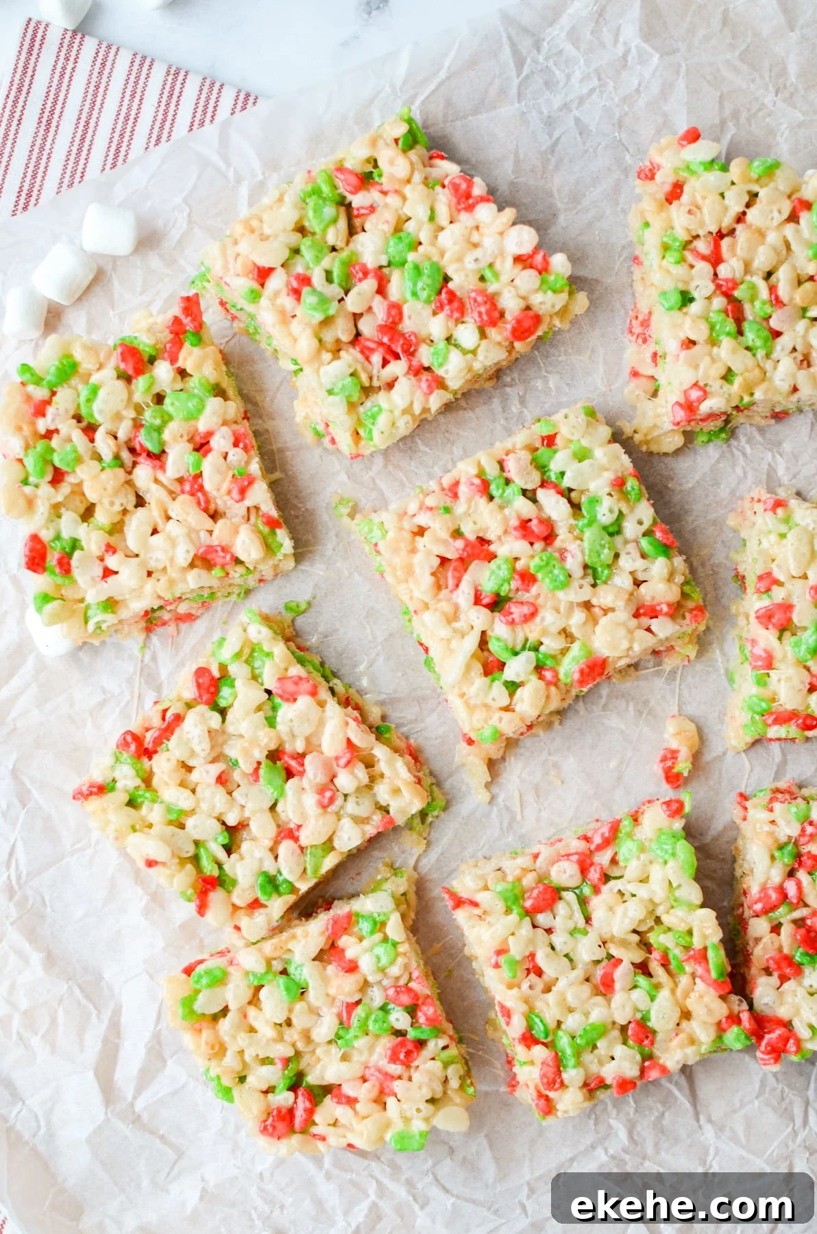 9 holiday Rice Krispies Treats cut on a piece of parchment.