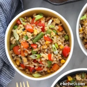 Three bowls of fried rice with vegetables.