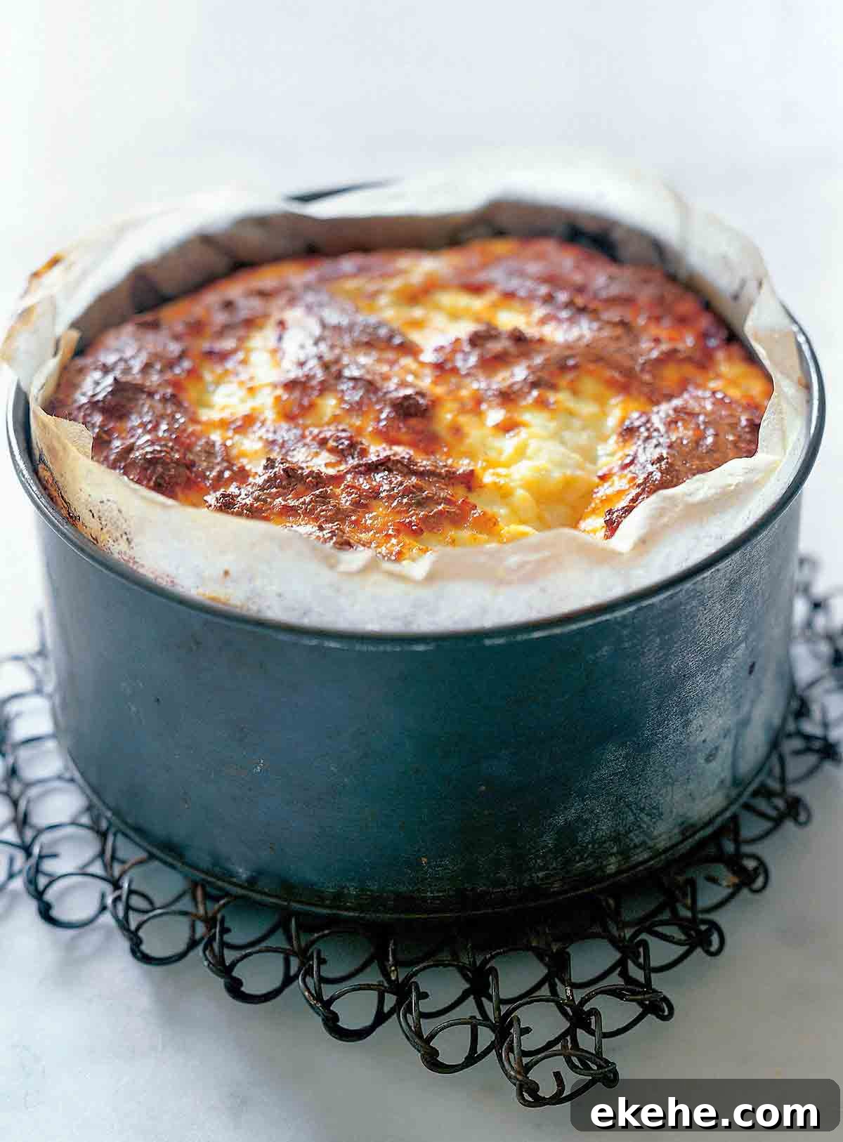 A parchment lined deep baking pan filled with baked ricotta.