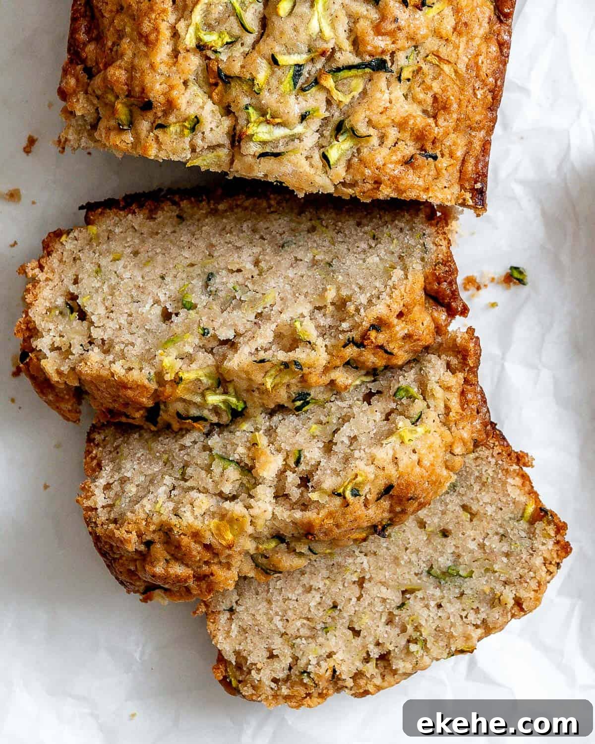 Slices of zucchini bread on white crinkled parchment paper.