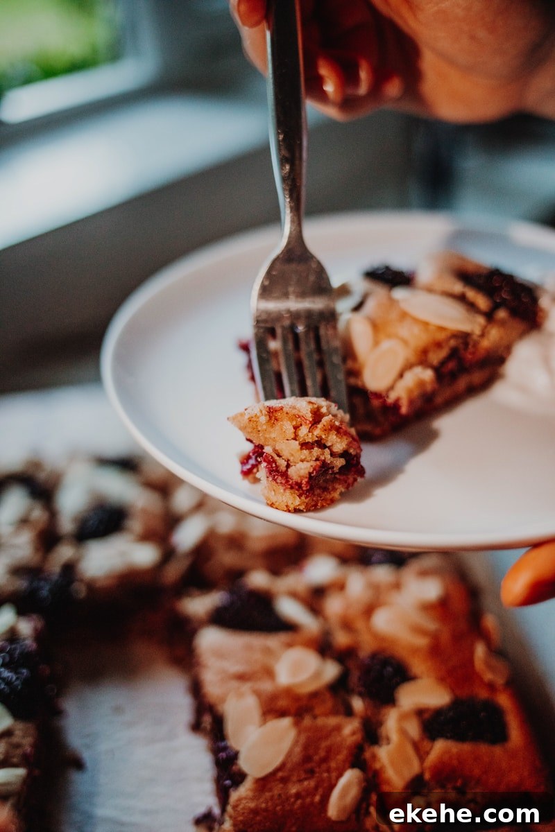 A blackberry bakewell bar being eaten on a plate