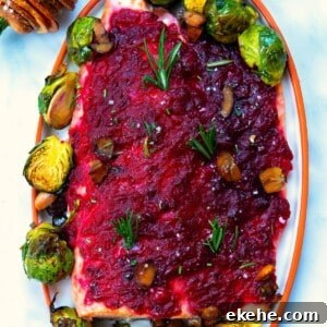 baked christmas salmon served with cranberry sauce an brussels sprouts on a white plate.