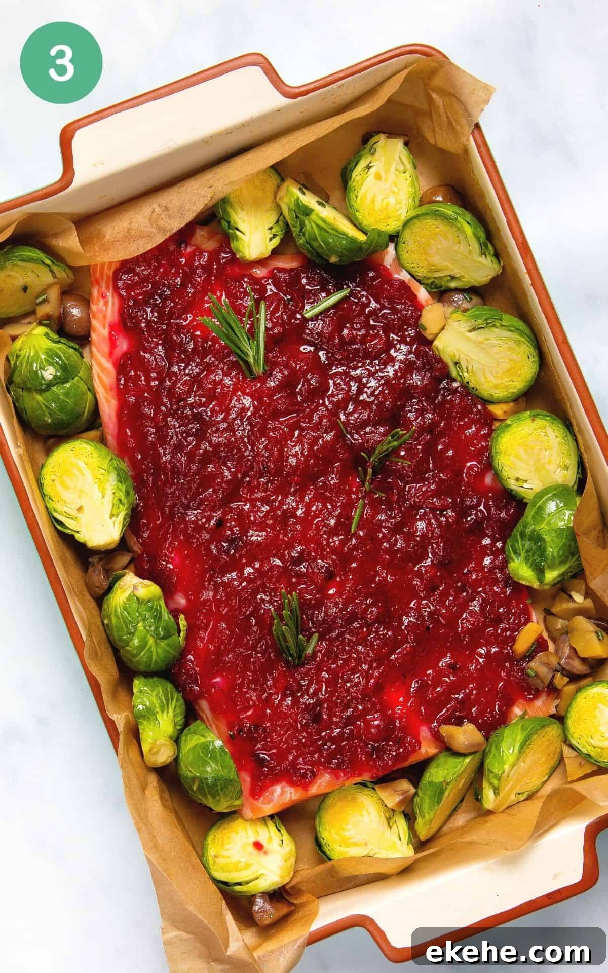 Placing the prepared salmon fillet with cranberry sauce on top into a baking dish.