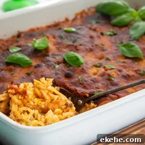 Baked Spaghetti in a white rectangle baking dish topped with basil leaves