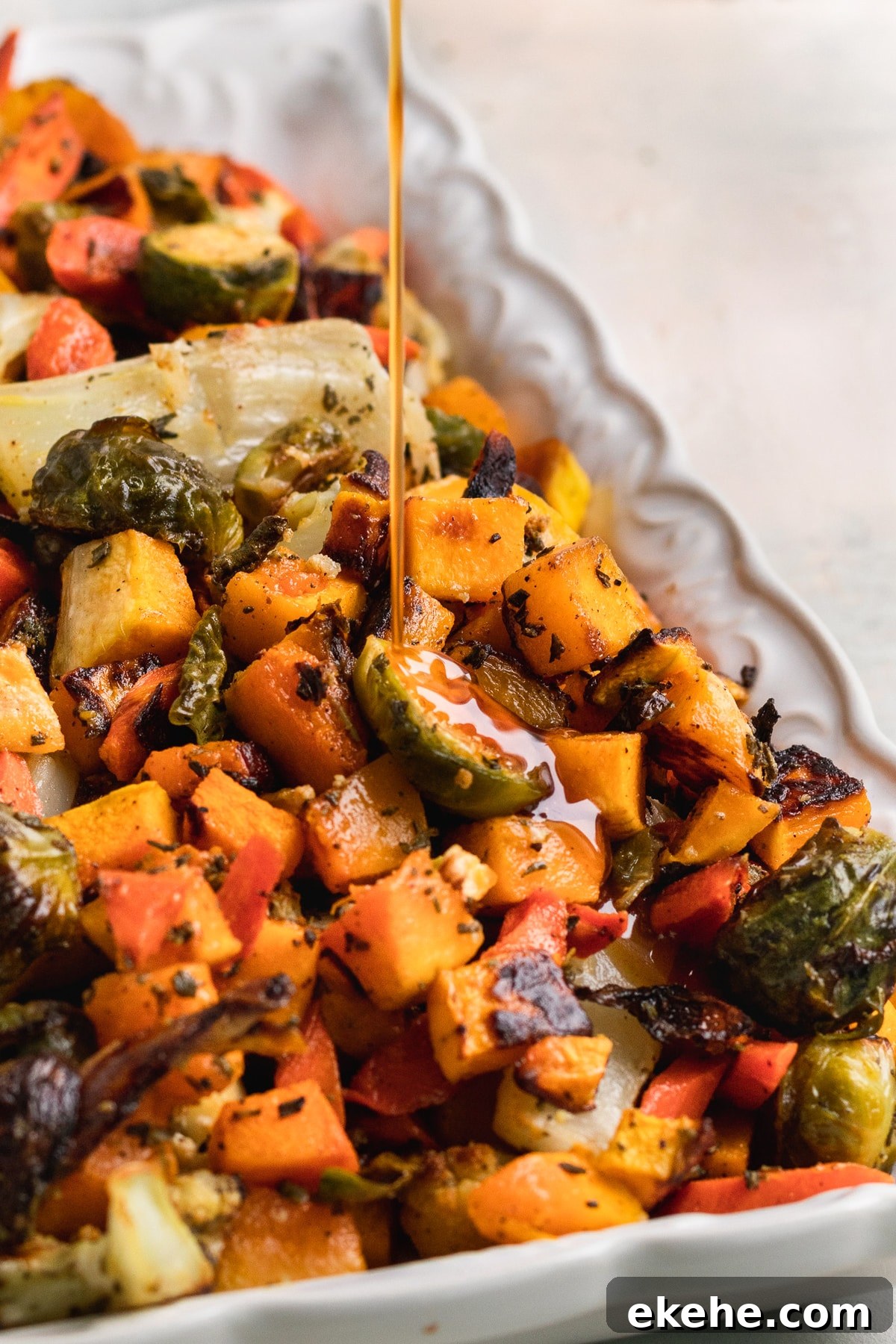 cider glaze being poured on roasted veggies. 