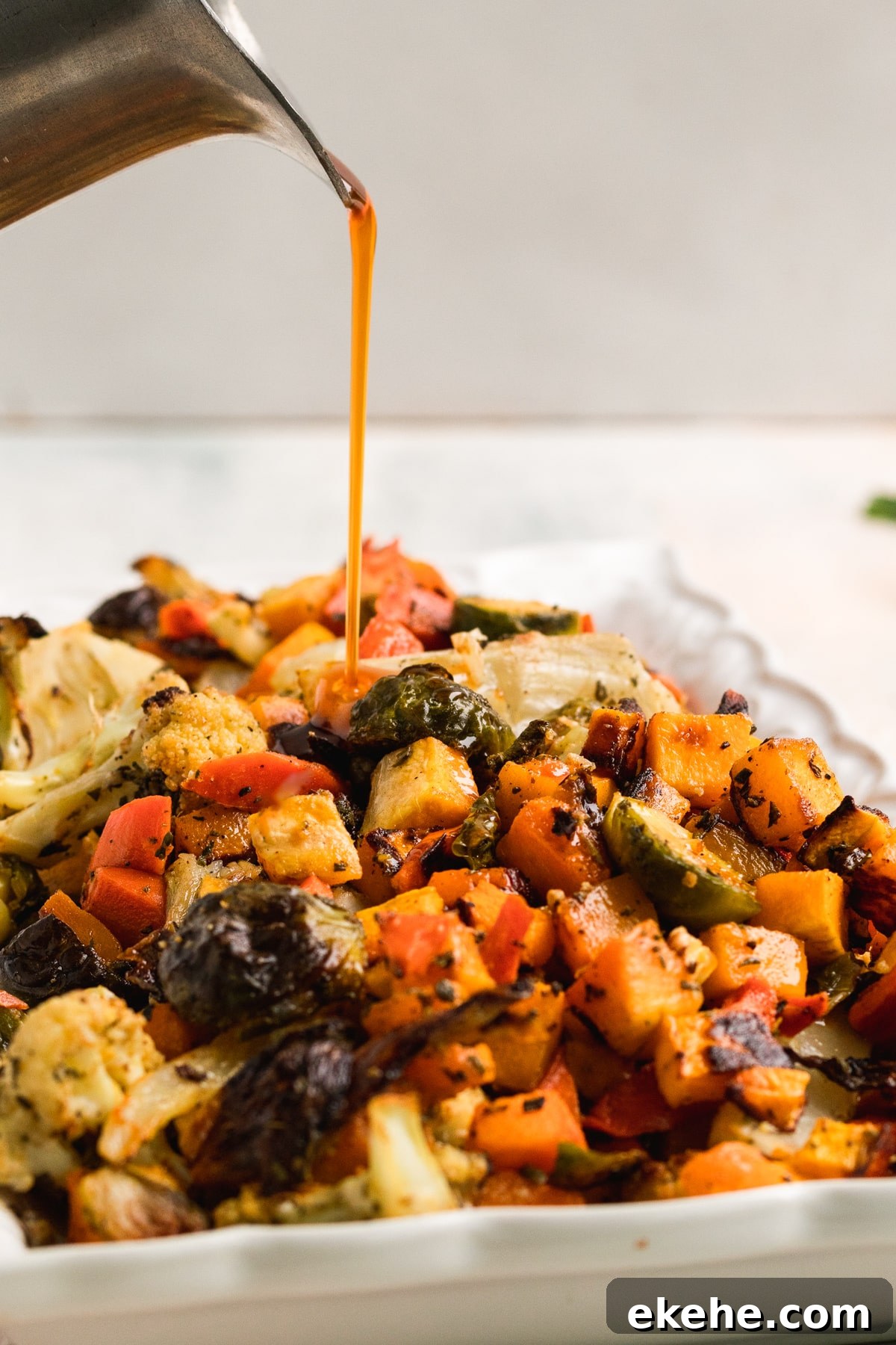 cider glaze being poured on a platter of roasted veggies. 