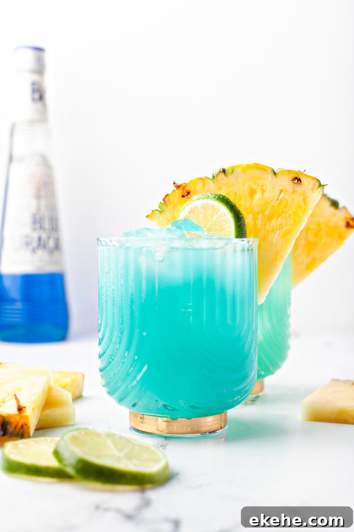 blue hawaiian cocktail in two glasses next to a bottle of blue curacao 