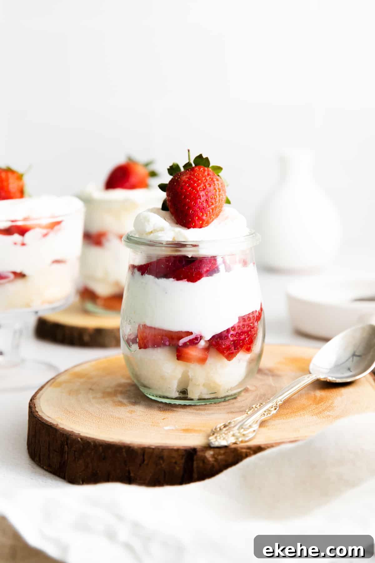 mini strawberry shortcake trifles in glass jars, showing their layers of angel food cake, fresh strawberries, and whipped cream