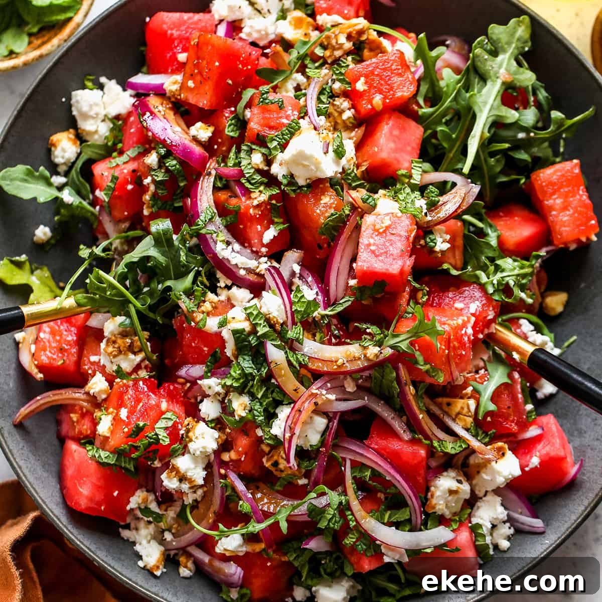 salad servers taking a scoop of Feta Watermelon Salad