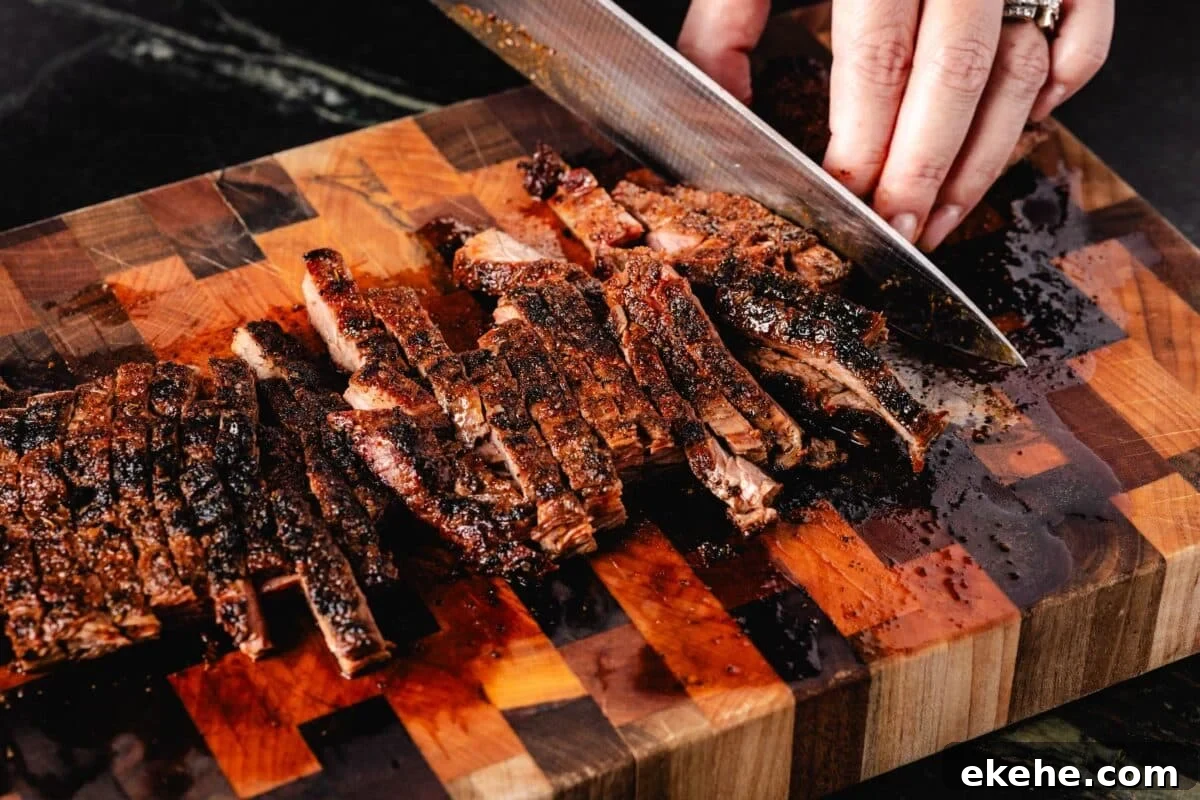 Steak on a wooden cutting board being sliced with a knife.