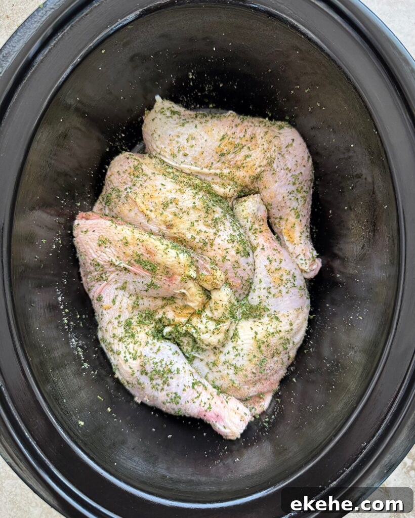 overhead shot of uncooked chicken leg quarters in a black slow cooker