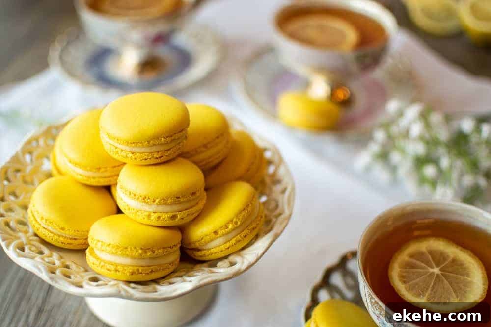 Lemon Macarons on white stand with three cups of lemon tea on a white cloth