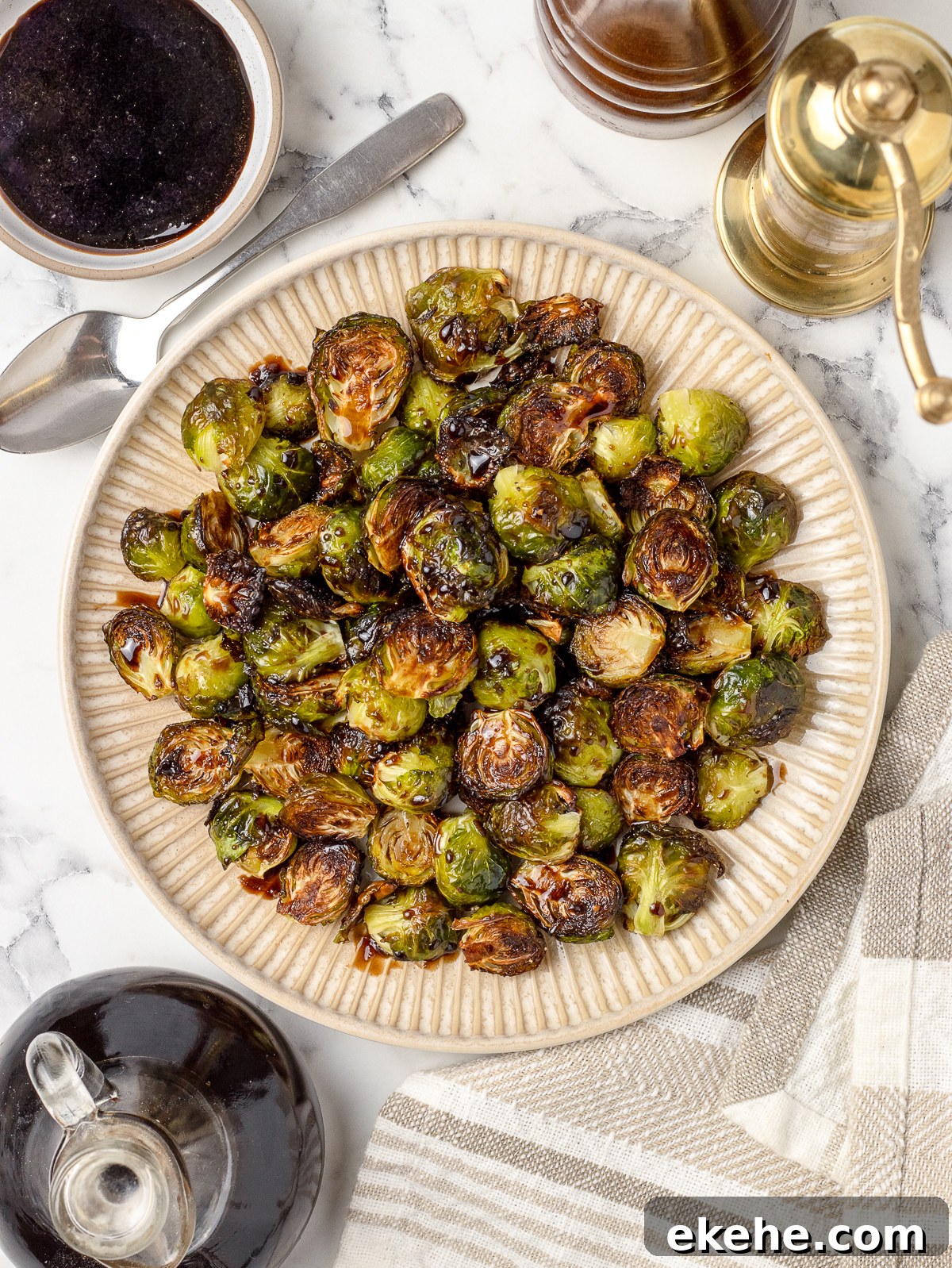 A large platter filled with roasted brussels sprouts. They are glazed in a balsamic honey sauce and there is more on the side for dipping.