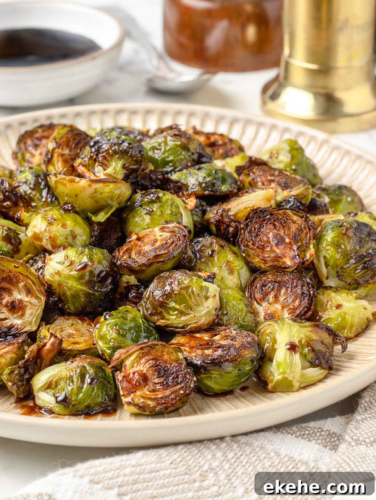 Platter of Balsamic Honey Brussels Sprouts glazed with a balsamic honey sauce. There is more in the background for serving.