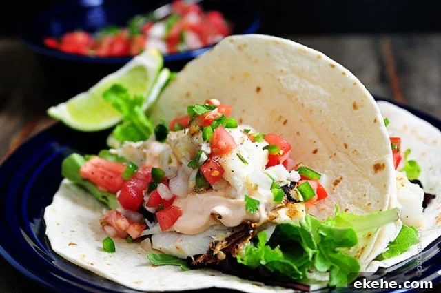 Fish Tacos  on blue plate with bowl of pico de gallo in background - addapinch.com