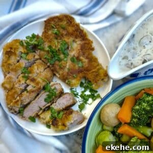 Crispy Crumbed Pork Chops with Mushroom Mustard Sauce 11 Crumbed pork chops on a plate, garnished with parsley. There is a jug of mushroom mustard sauce alongside.